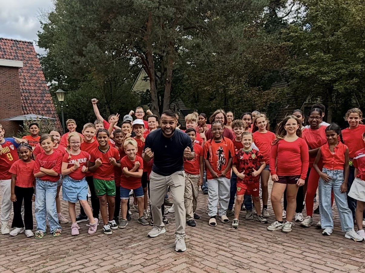 Cha Chi Versaci met een grote groep kinderen in rode shirts